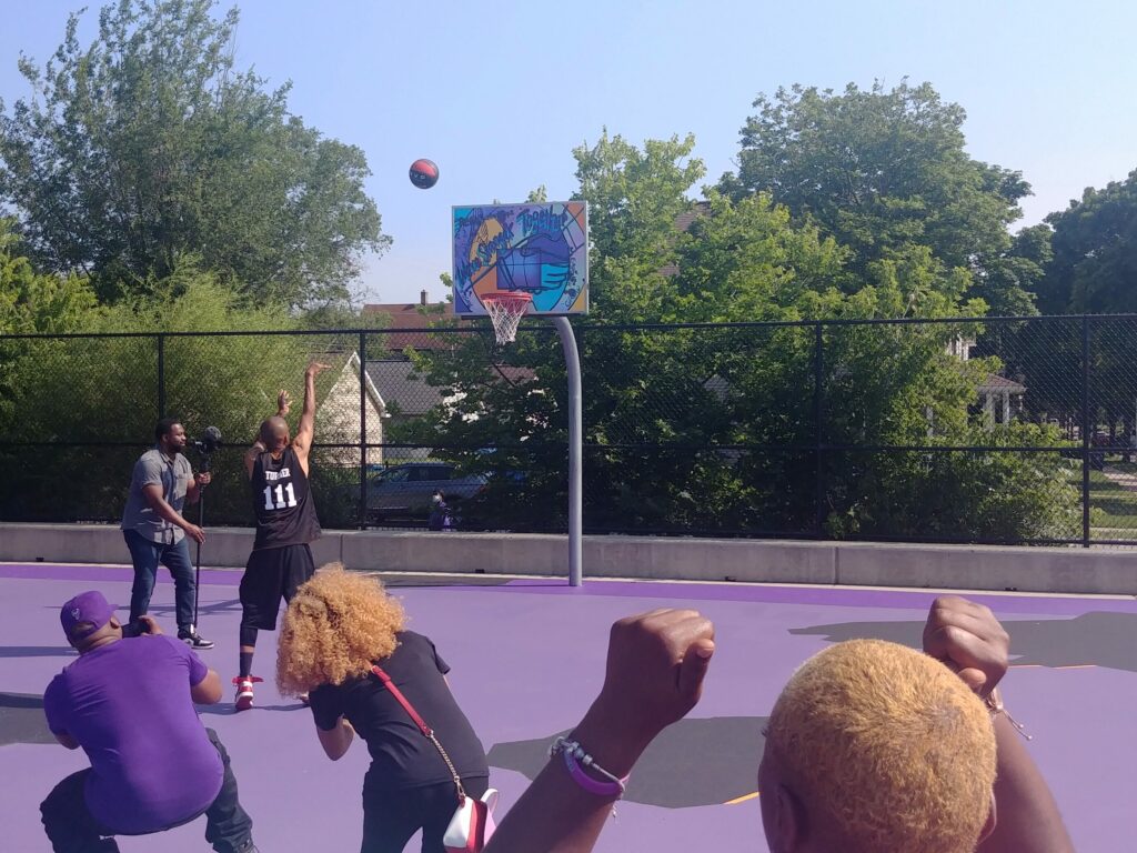 A basketball is being tossed while people surround a basketball hoop.